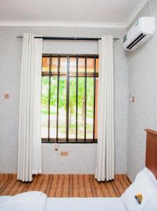 una camera da letto con finestra e tende bianche di Amarula Tree Hotel Mikumi a Mikumi