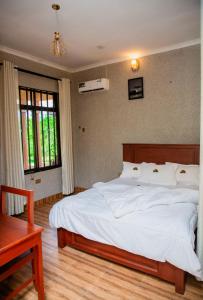 Un dormitorio con una gran cama blanca y una mesa en Amarula Tree Hotel Mikumi, en Mikumi