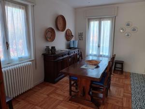 a dining room with a wooden table and a kitchen at Casa Tina in Verbania