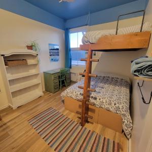 a bedroom with a bunk bed and a desk and a bunk bed at Auberge Internationale Le Tangon in Sept-Îles