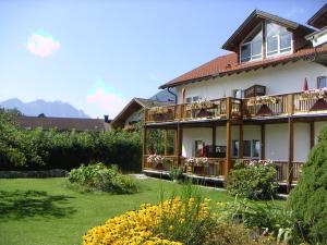 a house with balconies and a yard with flowers at Pension beim Krümmling in Reutte