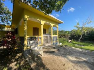 a yellow house with a chair in front of it at R&V VILLA in Negril