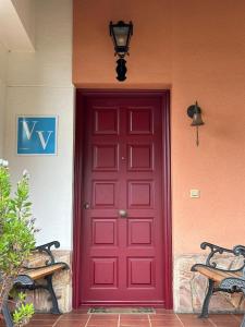 una puerta roja en una casa con dos bancos en SOPIEDRA II, en Nueva de Llanes