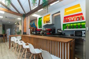 a restaurant with a bar with white chairs at Albergue Llanes Hostel in Llanes