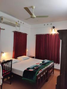 a bedroom with a large bed with red curtains at Kuttickattil Gardens Homestay in Kottayam +50 photos