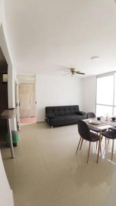 ein Wohnzimmer mit einem schwarzen Sofa und einem Tisch in der Unterkunft Cómodo Apartamento Amoblado en Condominio in Cúcuta