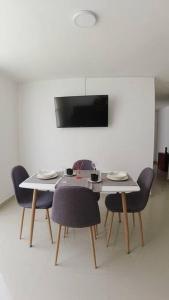 einen Esstisch mit Stühlen und einen TV in der Unterkunft Cómodo Apartamento Amoblado en Condominio in Cúcuta