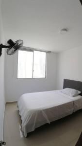 ein weißes Schlafzimmer mit einem Bett und einem Fenster in der Unterkunft Cómodo Apartamento Amoblado en Condominio in Cúcuta