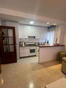 米尼奧的住宿－Playa grande Miño - Extremeiro,16，厨房配有白色橱柜和炉灶烤箱。