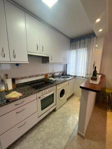 米尼奧的住宿－Playa grande Miño - Extremeiro,16，厨房配有白色橱柜和洗碗机。