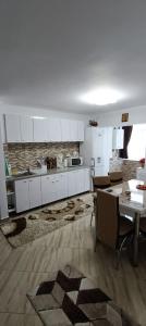 a kitchen with white cabinets and a table with chairs at Piano Apartament in Gura Humorului