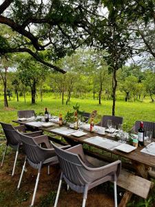 a long wooden table with chairs and bottles of wine at Amarula Tree Hotel Mikumi in Mikumi