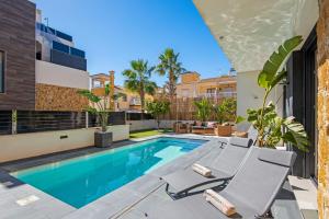 uma piscina com duas espreguiçadeiras ao lado de um edifício em Luxury Villa with Private Swimming Pool in Cabo Roig em Playas de Orihuela