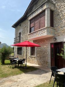 a table with a red umbrella in front of a building at Casa BellaTerra in Villasana de Mena