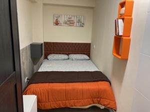 ein kleines Schlafzimmer mit einem Bett mit einer orangefarbenen Decke in der Unterkunft Windy in Salou