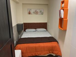 ein kleines Schlafzimmer mit einem Bett mit einer orangefarbenen Decke in der Unterkunft Windy in Salou