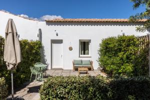 un patio con una silla, una mesa y una sombrilla en Quinta da Capelinha Agroturismo, en Tavira