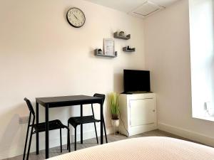 Habitación con mesa, 2 sillas y reloj en Cosy Modern 2 Bedroom Apartment bedroom with ensuite bathroom - Neath Road Port Talbot Near Briton Ferry Train Station, en Briton Ferry