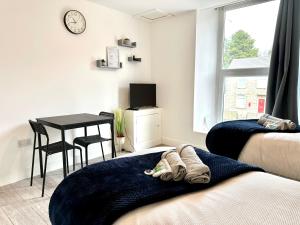 Cosy Modern 2 Bedroom Apartment bedroom with ensuite bathroom - Neath Road Port Talbot Near Briton Ferry Train Station في Briton Ferry: غرفة نوم مع مكتب وطاولة وسرير