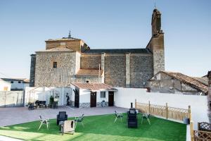 un grand bâtiment en pierre avec des chaises sur une pelouse verdoyante dans l'établissement Posada Real by Alterhome, à Velayos