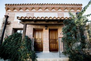 une maison en briques avec une porte en bois à l'avant dans l'établissement Posada Real by Alterhome, à Velayos