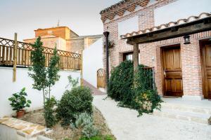 un bâtiment en briques avec une terrasse couverte et une clôture dans l'établissement Posada Real by Alterhome, à Velayos