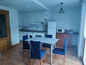 a kitchen with a white table and blue chairs at Apartamento Aran isaba in Isaba