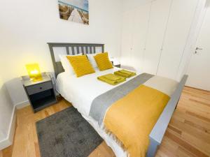 - une chambre avec un grand lit et des oreillers jaunes dans l'établissement Lisbon Charming Santos Apartment w/ Patio, à Lisbonne
