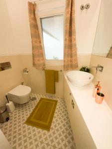 La salle de bains est pourvue d'un lavabo, de toilettes et d'une fenêtre. dans l'établissement Lisbon Charming Santos Apartment w/ Patio, à Lisbonne