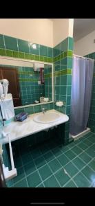 a green tiled bathroom with a sink and a shower at Comoda villetta con giardino in San Teodoro