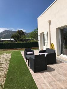 patio z 2 czarnymi krzesłami i trawą w obiekcie Villa T3 5p de 85m² avec jardin à CALVI w Calvi