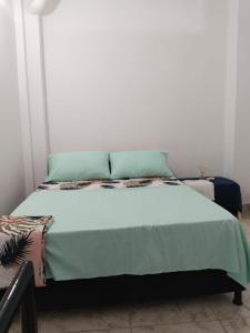 a bed with a green blanket and pillows on it at APARTAMENTO PUERTO TRIUNFO ANTIOQUIA in Puerto Triunfo