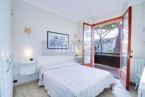 Habitación blanca con cama y balcón. en Mare appartamento ristrutturato e con posto auto en Castiglione della Pescaia