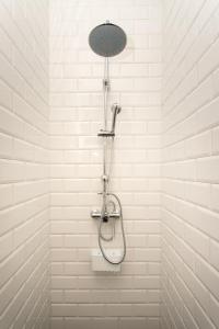 a shower in a bathroom with white tiles at Albergue Hostel Llanes in Llanes