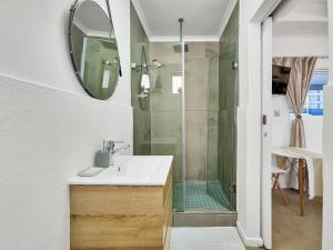 een badkamer met wastafel en douche met spiegel bij Unique Studio Close to Promenade in Kaapstad +7 foto's