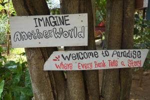 two signs on a tree with writing on them at Another World Hostel Sigiriya in Sigiriya