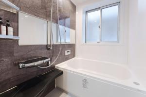 a bathroom with a white tub and a window at City House 暁 -akatsuki- in Osaka
