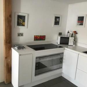 a white kitchen with a microwave and a stove at Prestwick Oak - 3 King Bed Ensuite Quirky Contemporary in Chiddingfold