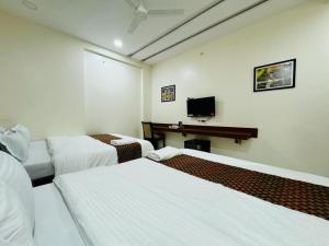 a hotel room with two beds and a desk at Hotel Sai Sneha in Shirdi