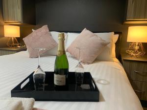 dwie butelki wina na tacy na łóżku w obiekcie New Modern house in Reading with free parking w mieście Caversham
