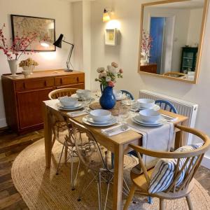una mesa de comedor con sillas y un jarrón azul con flores en The Yellow cottage on the hill., en Framlingham