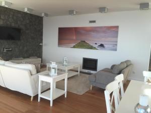 een woonkamer met witte meubels en een televisie bij Casa das Cinco in Angra do Heroísmo