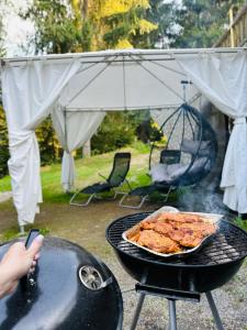 a person cooking food on a grill with an umbrella at Chata Kokava Línia tour 2 in Kokava na Rimavica