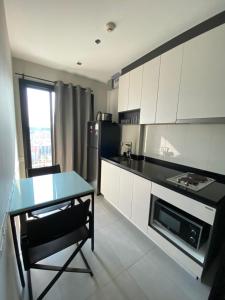a kitchen with white cabinets and a table and a refrigerator at The base in pattaya condo in Pattaya