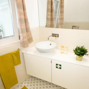 La salle de bains blanche est pourvue d'un lavabo et d'un miroir. dans l'établissement Lisbon Charming Santos Apartment w/ Patio, à Lisbonne