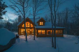 una baita di tronchi nella neve di notte di Private Hot Tub Sauna Ski Indoor Pool Nyctale a Mille-Isles