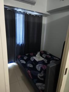 a small bed in a room with black curtains at Sea Residences MOA -PaulJade Place in Manila