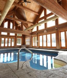 a large indoor swimming pool in a wooden building at Private Hot Tub Sauna Ski Indoor Pool Nyctale in Mille-Isles
