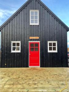 un edificio negro con una puerta roja y dos ventanas en Jóhannshús- tradational Icelandic house, en Hrepphólar
