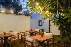 two wooden tables and chairs in a garden with lights at NİYAMA MARİNA Butik Hotel in Çeşme
